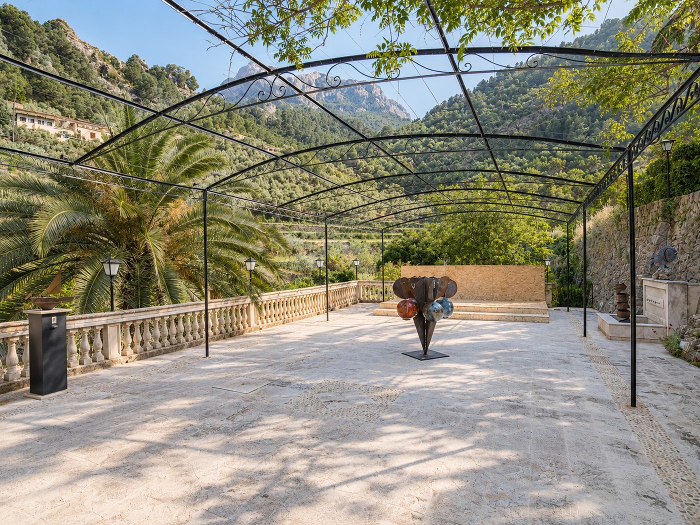 La Pérgola de hierro forjado sobre la terraza de piedra, con la Sierra de Tramuntana al fondo